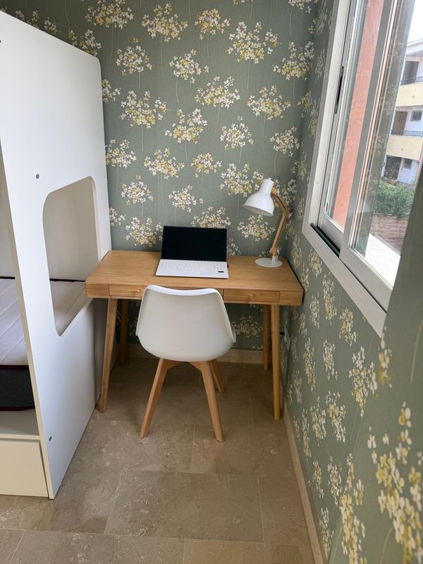 Escritorio de madera con lámpara en habitación infantil con papel pintado verde