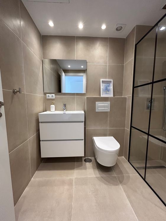 Baño reformado con ducha lluvia y mampara industrial negra